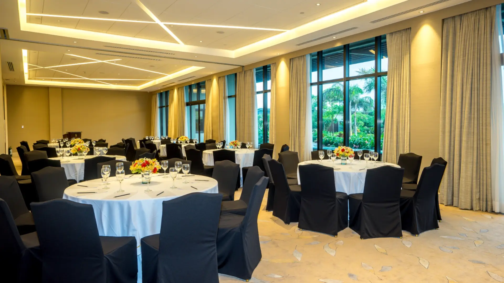 A beautifully decorated event venue in Cavite with round tables, black chairs, and floor-to-ceiling windows overlooking a garden.