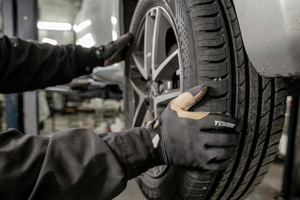 Auto mechanic checking car tire alignment and condition at a repair shop