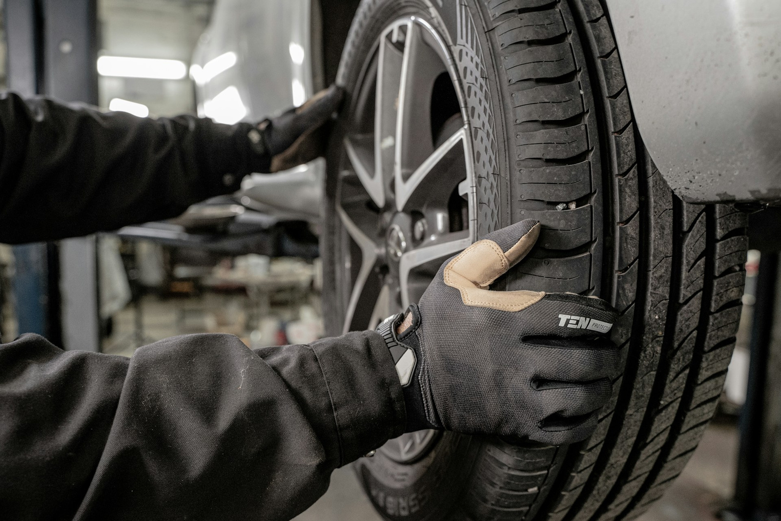 Auto mechanic checking car tire alignment and condition at a repair shop