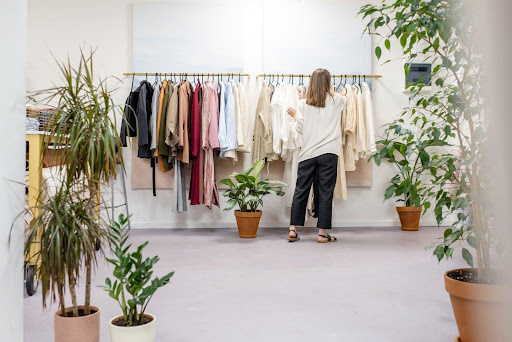Woman browsing a curated selection of clothes on racks in a minimalist fashion boutique.